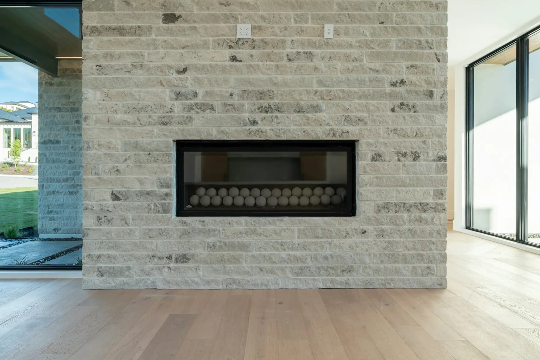 Contemporary stone fireplace built into a light brick wall by MCG Top Masonry