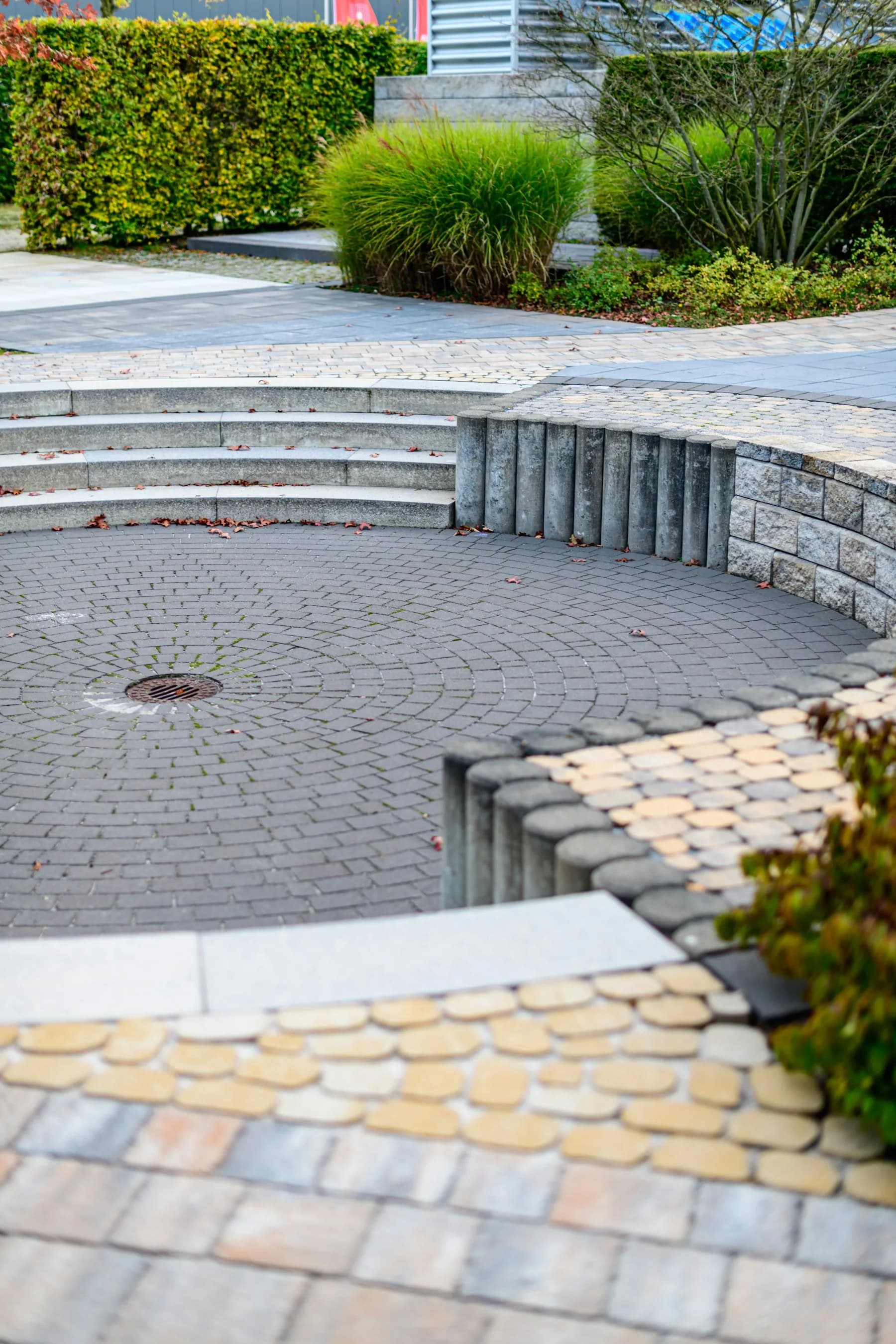Curved paved seating area with natural stone steps and greenery by MCG Top Masonry